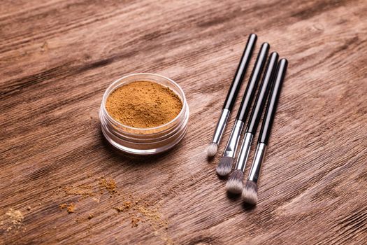 Mineral powder foundation with brush on a wooden background.