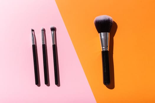 Various make-up brushes on pink background, top view. Cosmetics and beauty