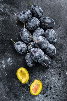 Garden plums on stone table. Black background. Top view.