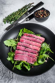 Tuna steak salad with arugula and spinach. White background. Top view.