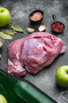 Raw pork meat and ingredients for roast set, with apple dry cider, on black dark stone table background