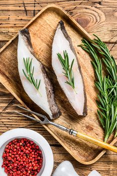 Raw halibut saltwater fish steak. wooden background. Top view.