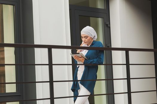 Beautiful muslim girl using digital tablet for communication with friend outdoor.