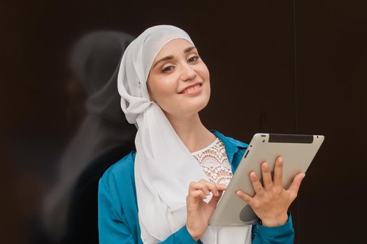 Young asian muslim woman in head scarf smile with mobile tablet.