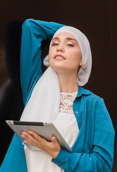 Modern Arabian muslim woman with tablet computer outdoors.