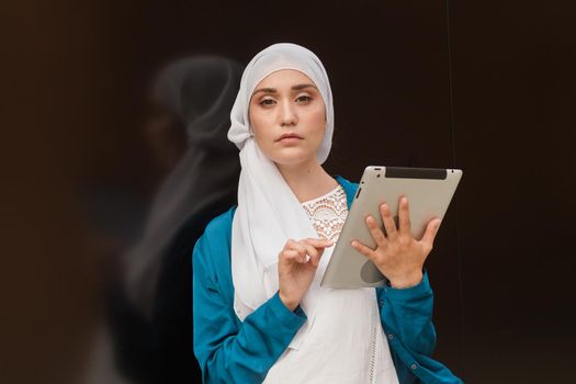 Modern Arabian muslim woman with tablet computer outdoors.