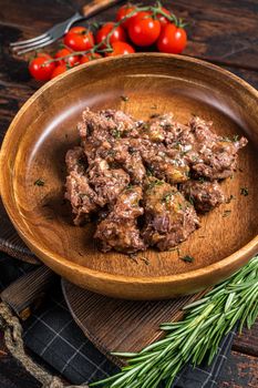 Stewed beef meat in a wooden plate. Dark Wooden background. Top view.
