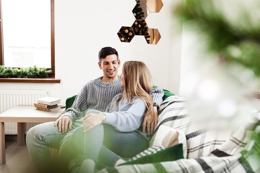 Sweet couple embracing on sofa at home during christmas holidays
