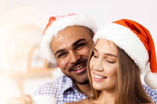 Cheerful attractive happy couple in Santa hats, close up portrait