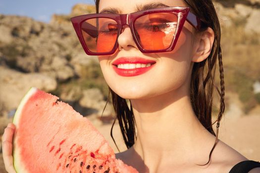cheerful woman in sunglasses and watermelon nature rocks. High quality photo