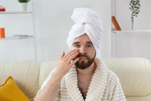 Bearded man applying eye patches on his face. Wrinkles and face home care for men
