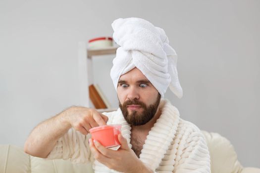 Handsome man holding cosmetic pink scrub for skin. Spa, body and skin care for man concept