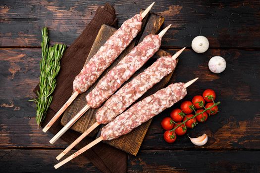 Raw mutton kebab shish skewers set, with grill ingredients, on old dark wooden table background, top view flat lay