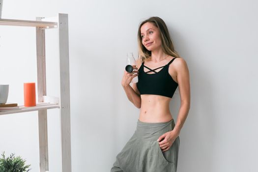 Sporty young woman drinking water after training at home. Active lifestyle and wellness