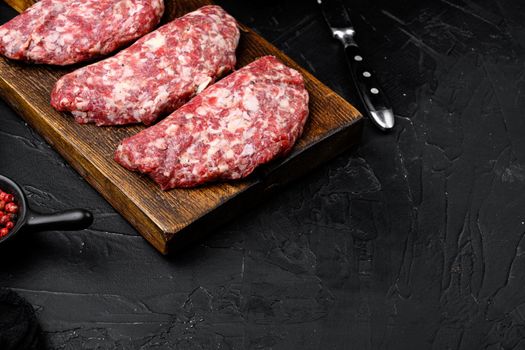 Raw beef patty set, on black dark stone table background, with copy space for text