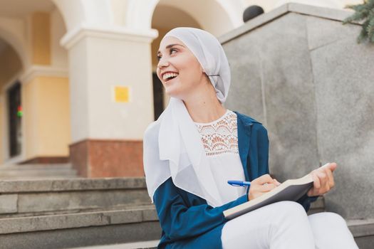 Arab female student sitting on stairs in downtown