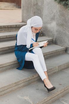 Arab female student sitting on stairs in downtown