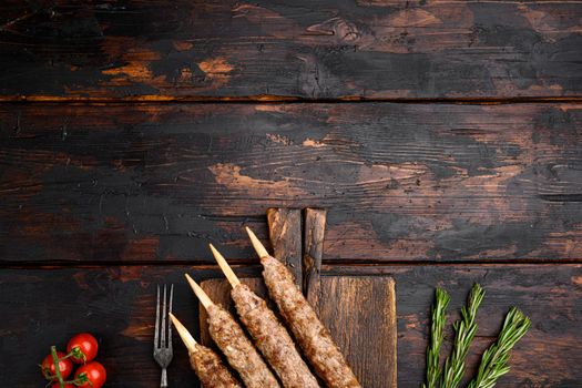 Tikka, shish and kofta kebabs set, on serving board, on old dark wooden table background, top view flat lay, with copy space for text