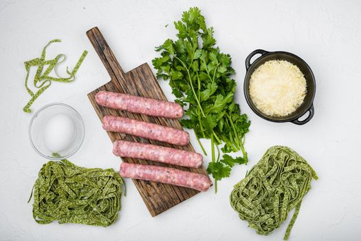 Fresh green pasta and sausages set, on white stone table background, top view flat lay