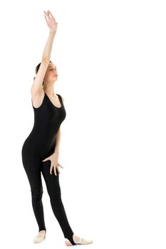 Gymnast girl in black sport outfit raising her hand. Attractive slim graceful teenage girl in leotard and headband performing exercise against isolated white background