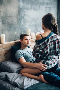 a guy and a girl sit on the bed in the room and look at each other