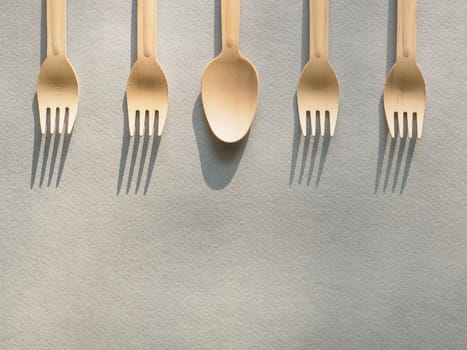 Wooden, biodegradable, four forks and one spoon.Concept of environment preservation and protection. Eco friendly disposable kitchenware utensils on blue craft paper background. Ecology, zero waste.
