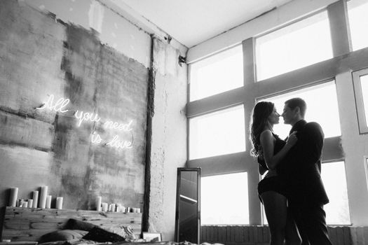 a guy and a girl hug each other, standing in the bed and window