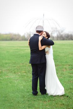 bride and groom on a rainy wedding day walking under an umbrella