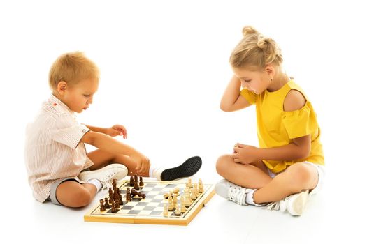 Couple boy and girl playing a board game of chess, thinking about the action and sitting on the floor. isolated on white background.