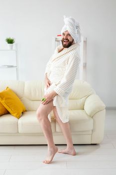 Portrait of cheerful guy wear turban towel makes himself a massage with massage brush. Male skin care and spa concept