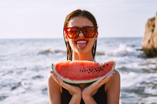 cheerful woman in sunglasses eating watermelon by the ocean. High quality photo