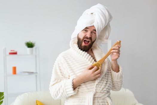 Funny handsome man pretends to play on massage brush as a guitar. Fun, spa and humor concept