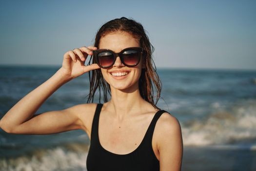 cheerful woman in black swimsuit sunglasses ocean travel. High quality photo