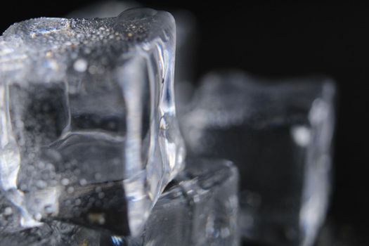 Ice cubes melt lie on a black background with a text close-up.