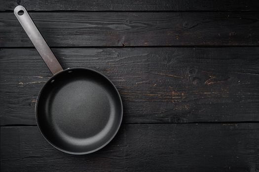 Cast iron frying pan set with copy space for text or food with copy space for text or food, top view flat lay, on black wooden table background