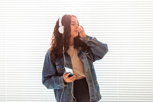 Young peaceful pregnant woman listens to pleasant classical music using smartphone and headphones. Concept of positive attitude before childbirth