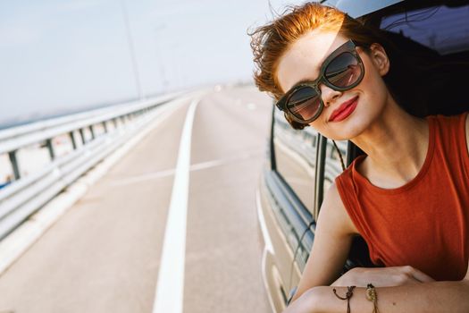 cheerful woman peeking out of the car window trip adventure lifestyle. High quality photo