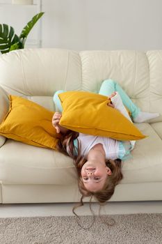 Child with a cast on a broken wrist or arm smiling and having fun on a couch. Positive attitude, recovery and kid.