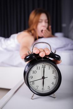 woman sleeping and wake up to turn off the alarm clock in the morning