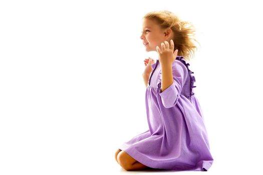 A strong wind blows on the face and clothes of a beautiful little girl of school age. Hair and clothes fluttering in the wind, and the girl is glad. Isolated on white background