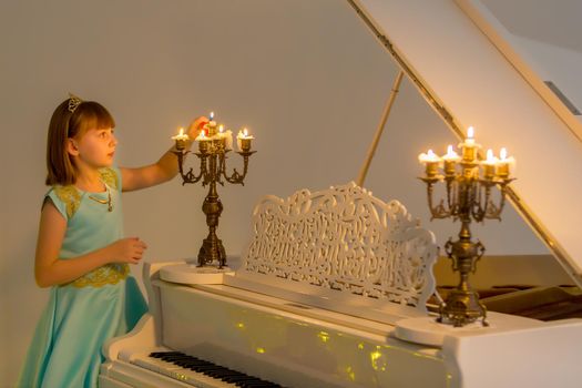 Romantic little girl lights candles on Christmas night. Family holidays concept.