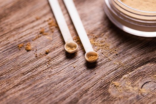 Mineral powder of different colors with spoon dispenser for make-up on wooden background.