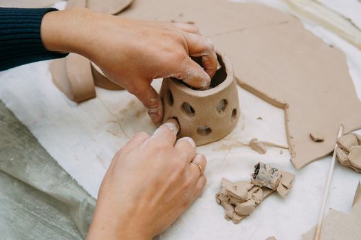 Women's hands knead clay, drawing elements of the product. Production of ceramic products at the master class on ceramics. Close-up.