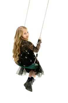 Beautiful little girl swinging in the studio on a swing. Concept of a happy childhood, family well-being.