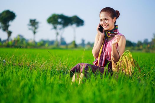 farmer woman calling on the mobile phone in a rice field, Thailand