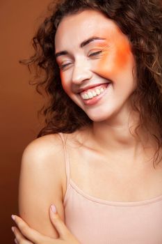 young pretty girl with curly hair posing cheerful on brown background, lifestyle people concept closeup