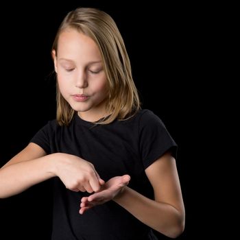 Pretty girl posing with closed eyes. Close portrait of beautiful blonde teenage girl in black t-shirt gesturing against black background.