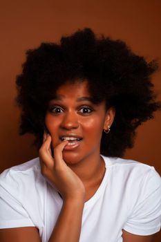 pretty young african american woman with curly hair posing cheerful gesturing on brown background, lifestyle people concept closeup