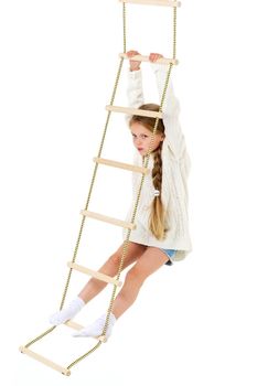 The girl climbs the rope ladder. Cheerful child on a white background. Active healthy lifestyle concept