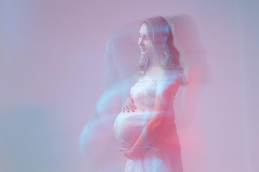 Elegant pregnant young woman standing wearing light fabric. Pregnancy, fantasy and fairy tale.
